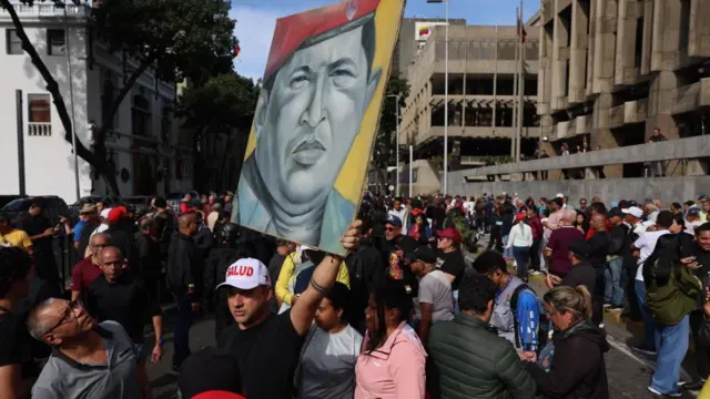 Crowds holding picture of late president Hugo Chavezas gather outside Mireflores Palace