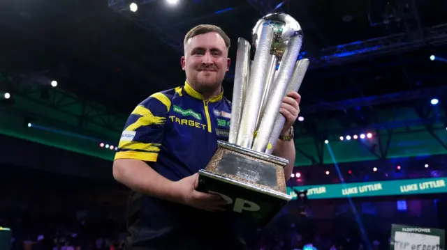 Luke Littler holds the World Championship trophy
