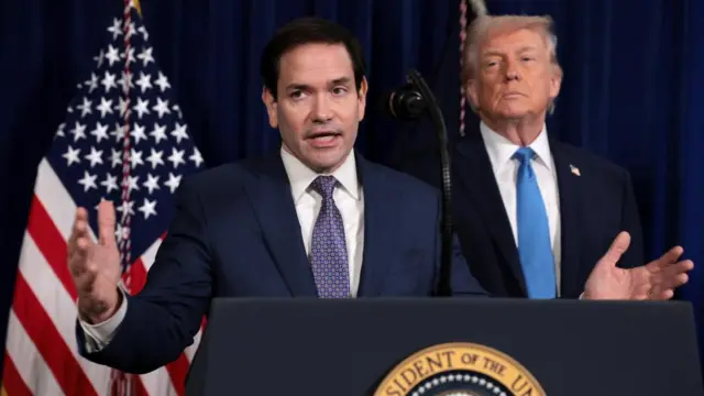 Secretary of State Marco Rubio gestures while President Donald Trump stands behind him