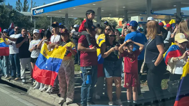 Images of a crowd gathered holding Venezuelan flags