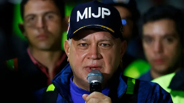 Hình ảnh Bộ trưởng Nội vụ Venezuela Diosdado Cabello đang phát biểu tại một cuộc mít tinh năm ngoái. Ông đội mũ có chữ 'MIJP' ​​và đang nói vào micro.