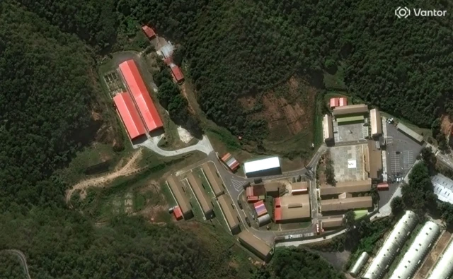 An aerial view of a compound of buildings surrounded by thick forest
