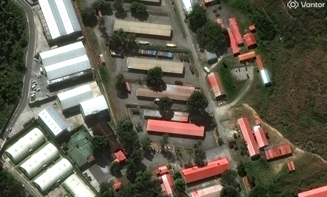 An aerial view of a compound of buildings with red roofs and silver ones