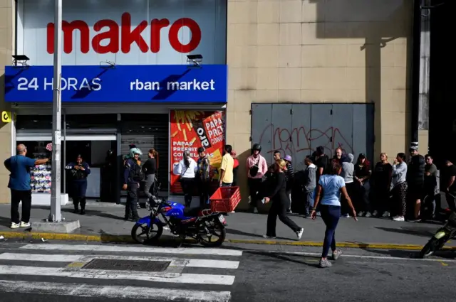 People queue at a supermarket in Caracas
