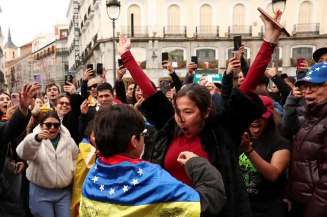 A woman celebrates next to a boy wrapped in a Venezuelan flag, as people react to the news after U.S. President Donald Trump said the U.S. has struck Venezuela and captured its President Nicolas Maduro, in Madrid, Spain, January 3, 2026.