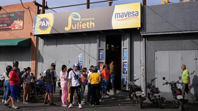 People queue outside a shop in Caracas