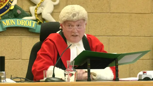 Mr Justice Soole in court wearing red and white robes and a wig