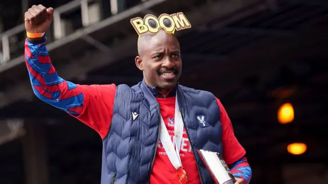 Jean-Philippe Mateta with a big hat saying 'boom' on his head