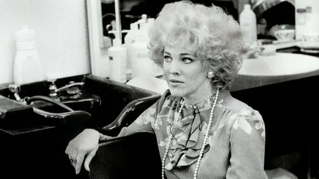 A black and white photo showing Catherine O'Hara in costume behind the scenes of SCTV
