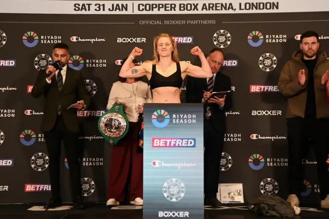 Ellie Bouttell flexing her biceps on the scales