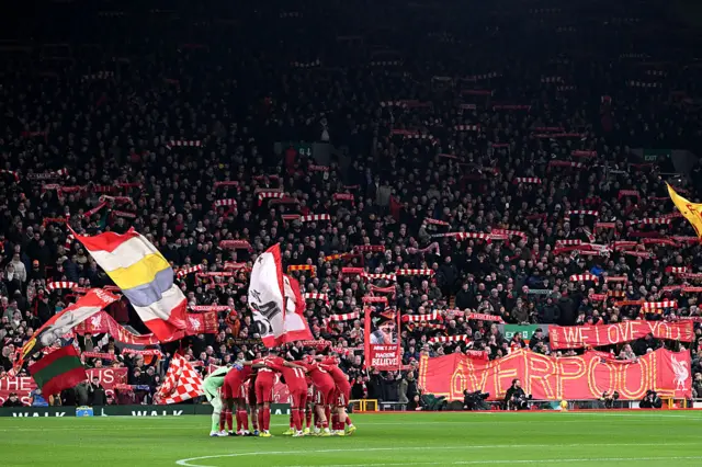 Liverpool players huddle in front of the kop