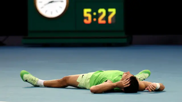Carlos Alcaraz lies on the floor
