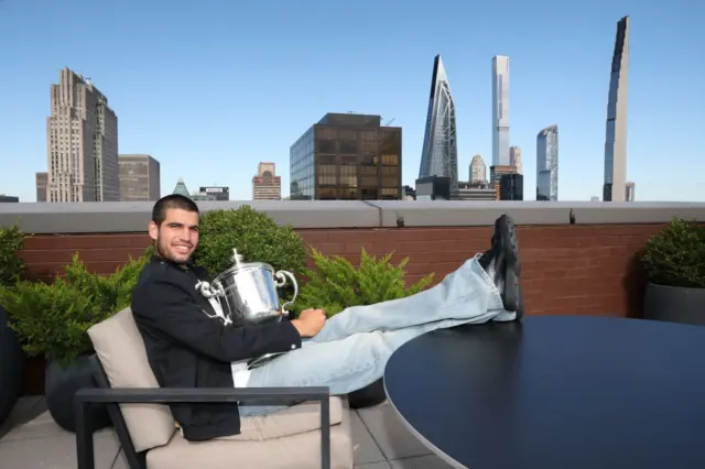 Carlos Alcaraz poses with the US Open trophy with the New York skyline behind