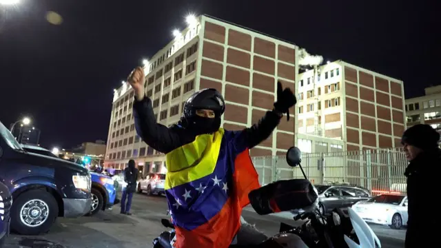 A Venezuelan supporter of the US miltary intervention in Venezuela celebrates in front of the Metropolitan Detention facility in the Brooklyn
