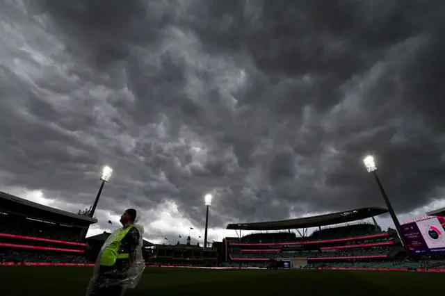 SCG with dark clouds and a steward wearing a plastic mac in the foreground