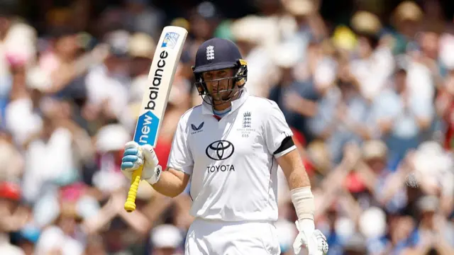 Joe Root of England raises his bat after reaching 50 runs