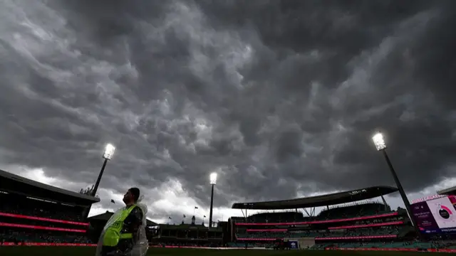 A security guard stands in the outfield as rain falls on day one of the fifth Ashes cricket Test