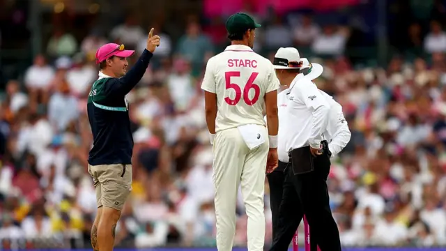 A groundskeeper signals for the covers as a light delay is called during