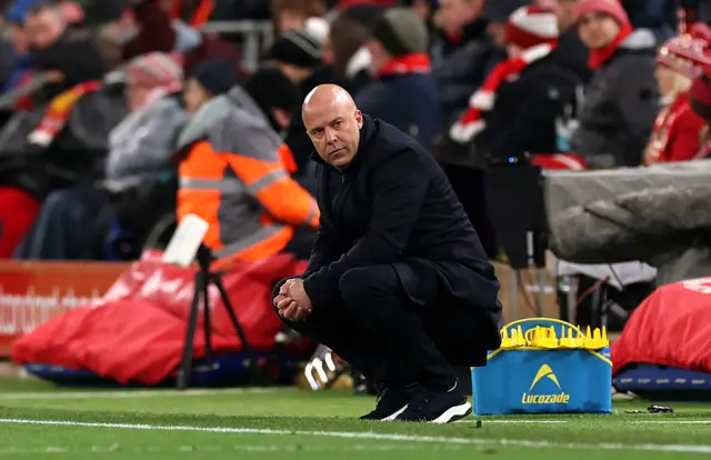 Arne Slot crouching down on the sideline