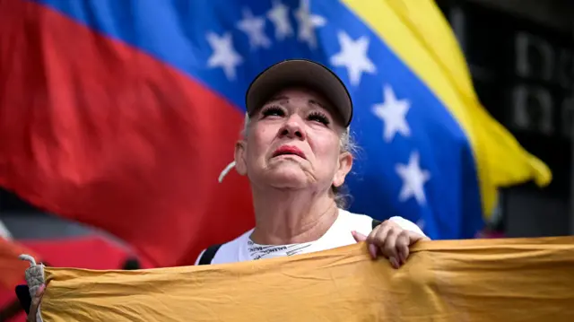A woman standing in front of a Venezuelan flag in Caracas, Venezuela