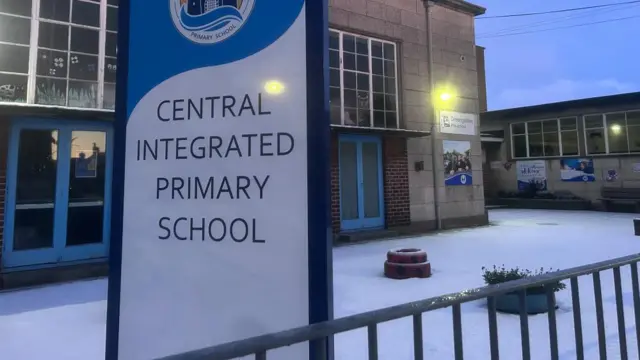 Snow can be on the ground next to a sign saying Central Integrated Primary School