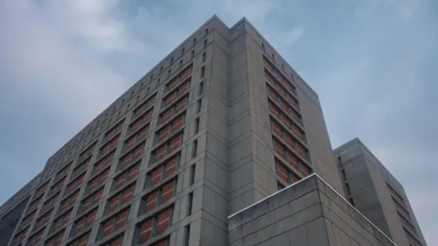 The Metropolitan Detention Center, a large, concrete building towering above.