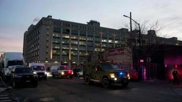 An armoured vehicle travels down a street followed by police vehicles