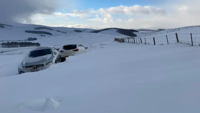 View of snow and two cars stranded in rural Aberdeenshire