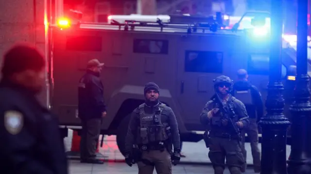 Blue and red emergency lights flashing on a secure vehicle, surrounded by law enforcement