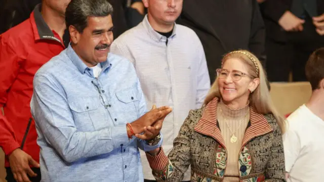 Flores and Maduro hold hands, smiling.