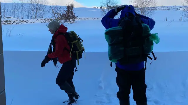 View of two women walking through thick snow