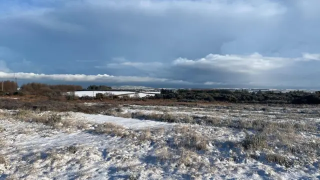 A snow-covered field with dark clouds in the sky