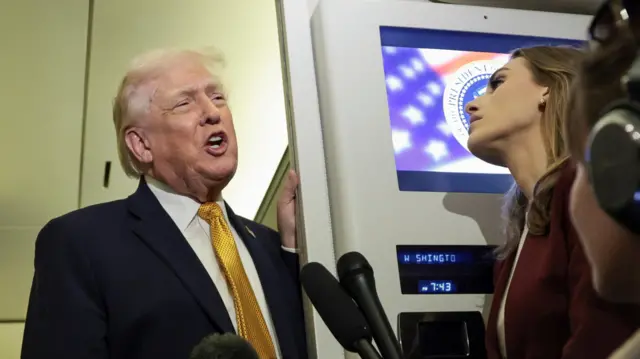 US President Donald Trump speaks to reporters aboard Air Force One en route from Florida