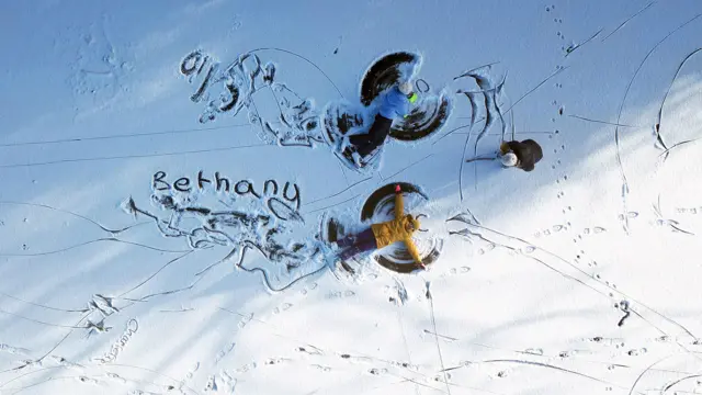 People write their names and make snow angels on a frozen, flooded field