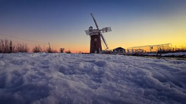 A windmill is seen at sunrise in the snow in Norfolk