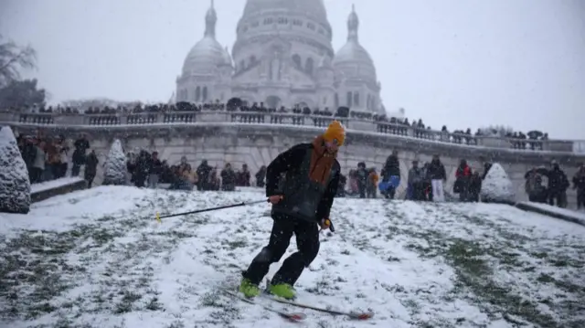 A man skis down a slope in front of the Sacre Coeur Basilica at the Butte Montmartre in Paris as winter weather with snow and cold temperatures hits a large part of the country, France, January 5, 2026