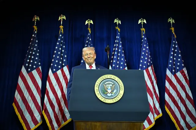 Trump at podium with flags behind him.