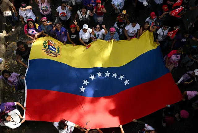 Women wave a big Venezuelan flag during a rally in support of ousted Venezuela's President Nicolas Maduro and his wife Cilia Flores in Caracas.