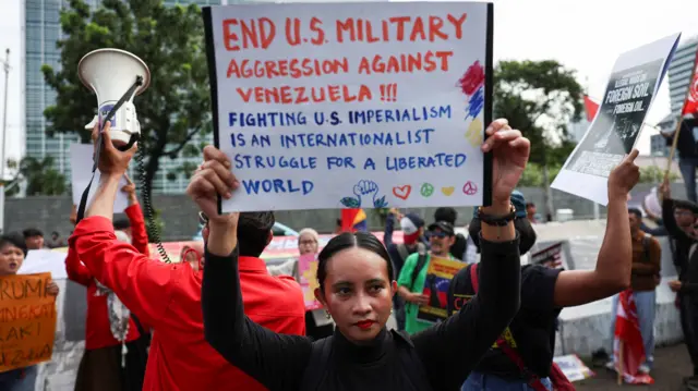 A protester holds up a sign saying "End US military aggression against Venezuela"