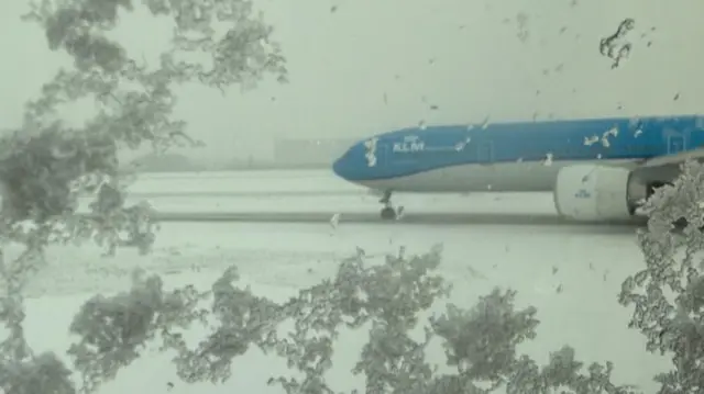 A plane on a snow runway. There are lots of snowflakes on the window.