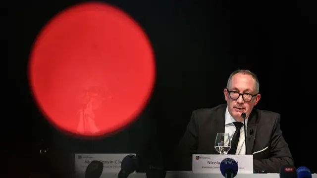 The mayor speaking at the news conference, and there is a red glare on the camera, which is putting a huge red circle next to him.