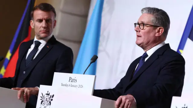 Macron and Starmer stand at podiums in front of flags