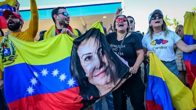 People hold a Venezuelan flag with a picture of opposition leader, Nobel peace laureate Maria Corina Machado as they react to the news