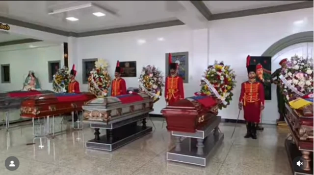 Soldiers stand behind five flag drapped coffins in Cenezuela