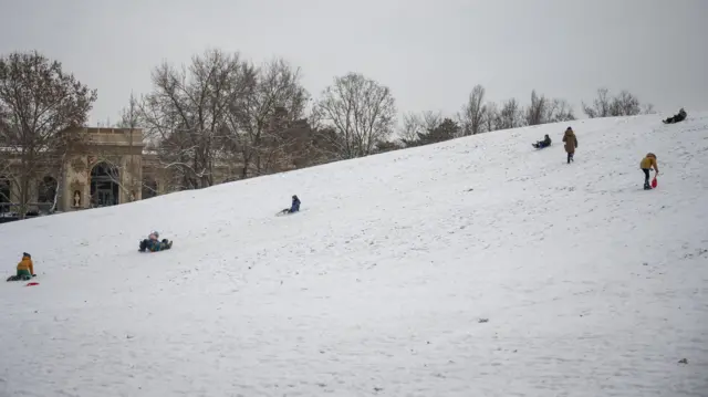 People go sledding on a snowy slope in Hungary
