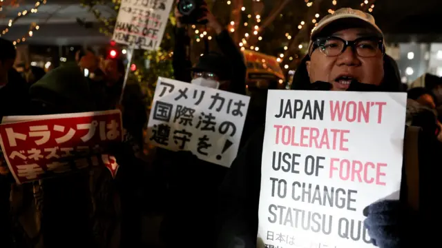 Protestors hold signs in English and Japanese, reading 'Japan won't tolerate use of force to change status quo'