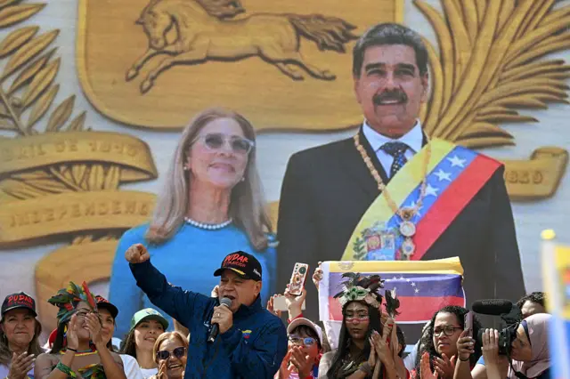 Venezuela's Minister of Interior Diosdado Cabello delivers a speech during a women's rally in support of Maduro. Next to him are women supporters and behind him is an image projection of Maduro and his wife Cilia Flores