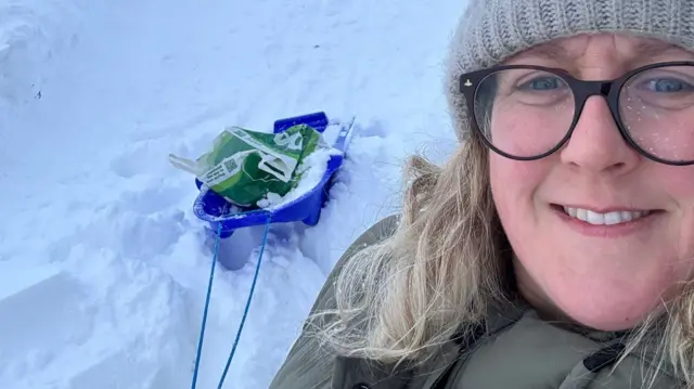 Alyson with a sledge bringing food back to her house that has been dropped off by a local farmer