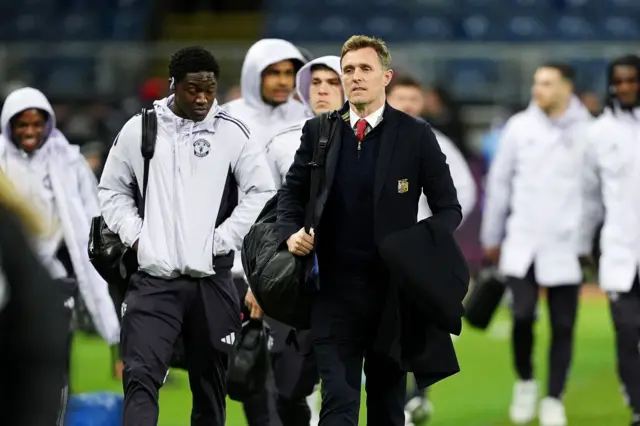 Manchester United's Kobbie Mainoo (left) and interim head coach Darren Fletcher (centre right) arrive ahead of the Premier League match at Turf Moo