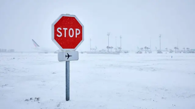 Stop sign at an airport covered in now